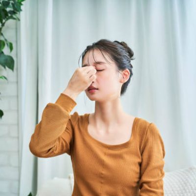 A young woman wearing loungewear suffering from a headache in her room